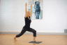 Frau macht Yogaübung und steht mit einem Fuß auf Step Fit