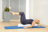 Frau in Rückenlage auf dem Pilates Roller